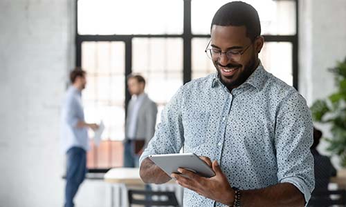 Man smiles down at iPad as he prepares the software architecture to function effectively for the business.